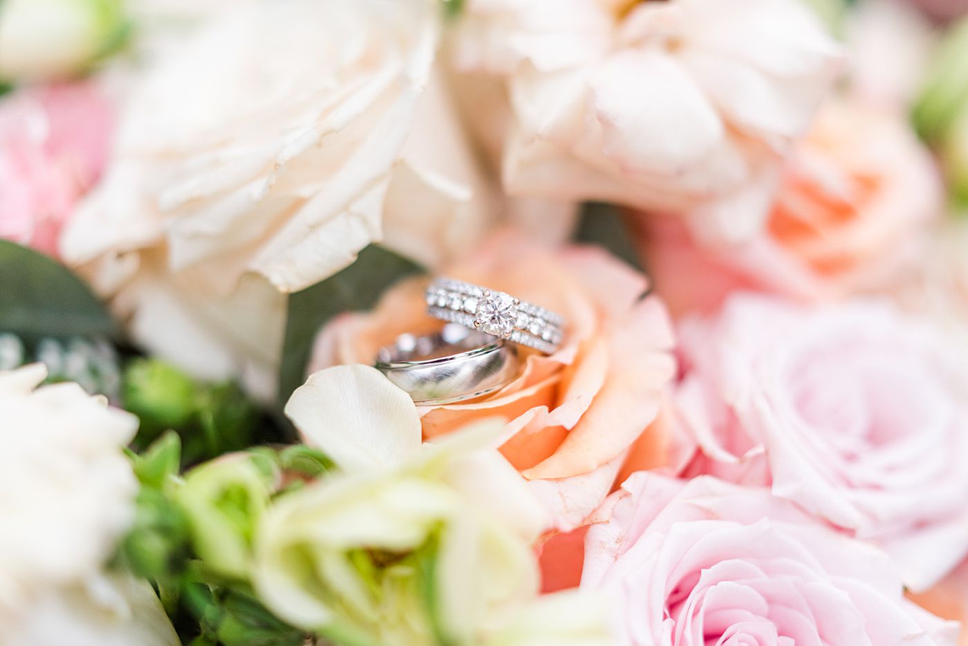 a wedding band and diamond ring sitting on a bouquet of roses