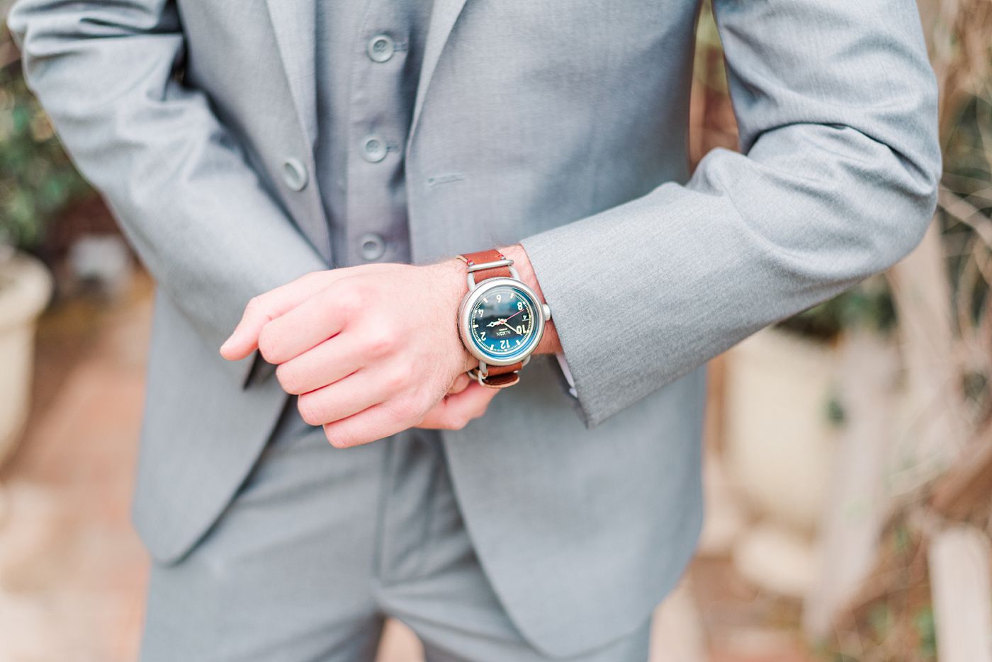 a man in a grey suit putting a watch on