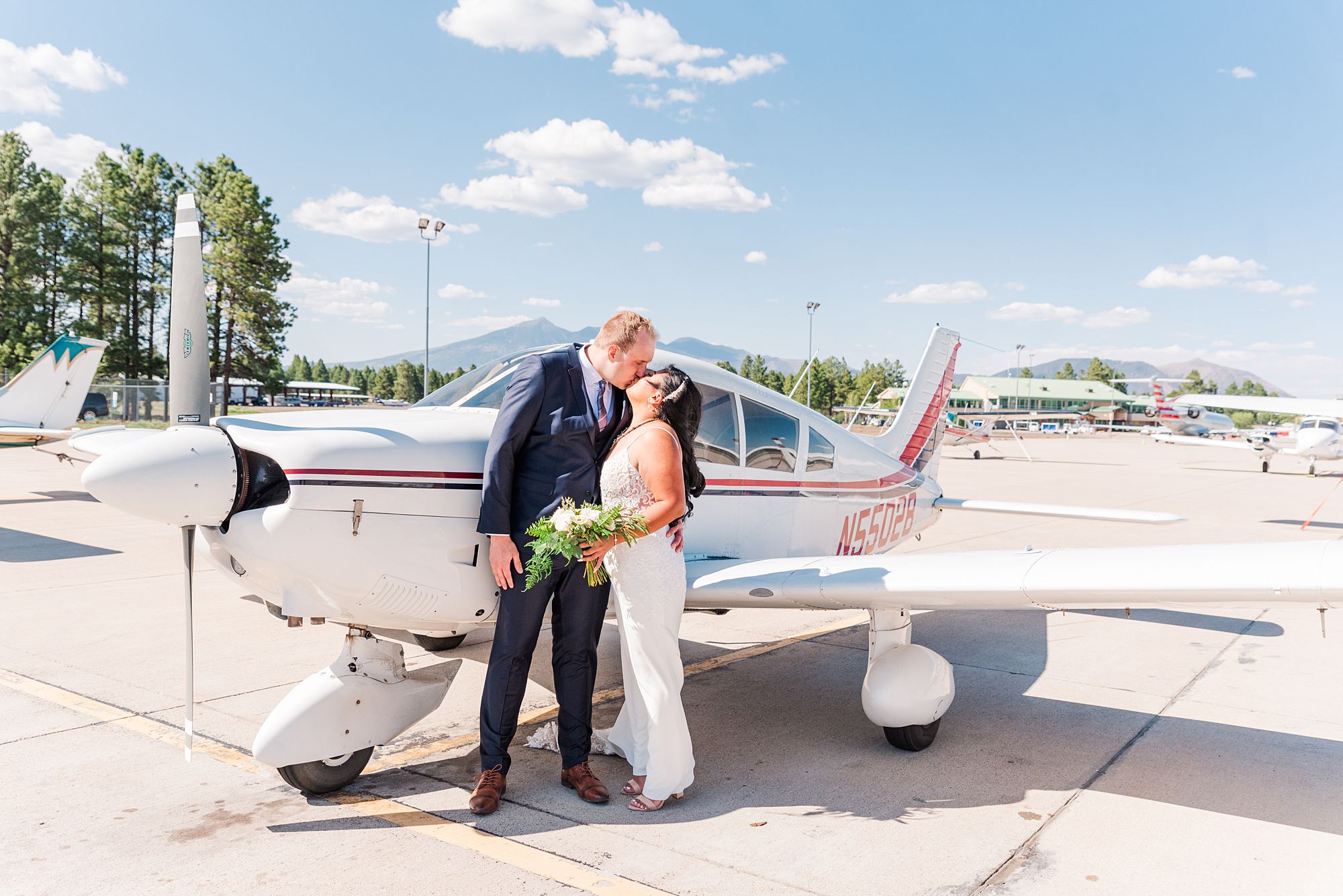 a man and woman kissing in front of an airplane