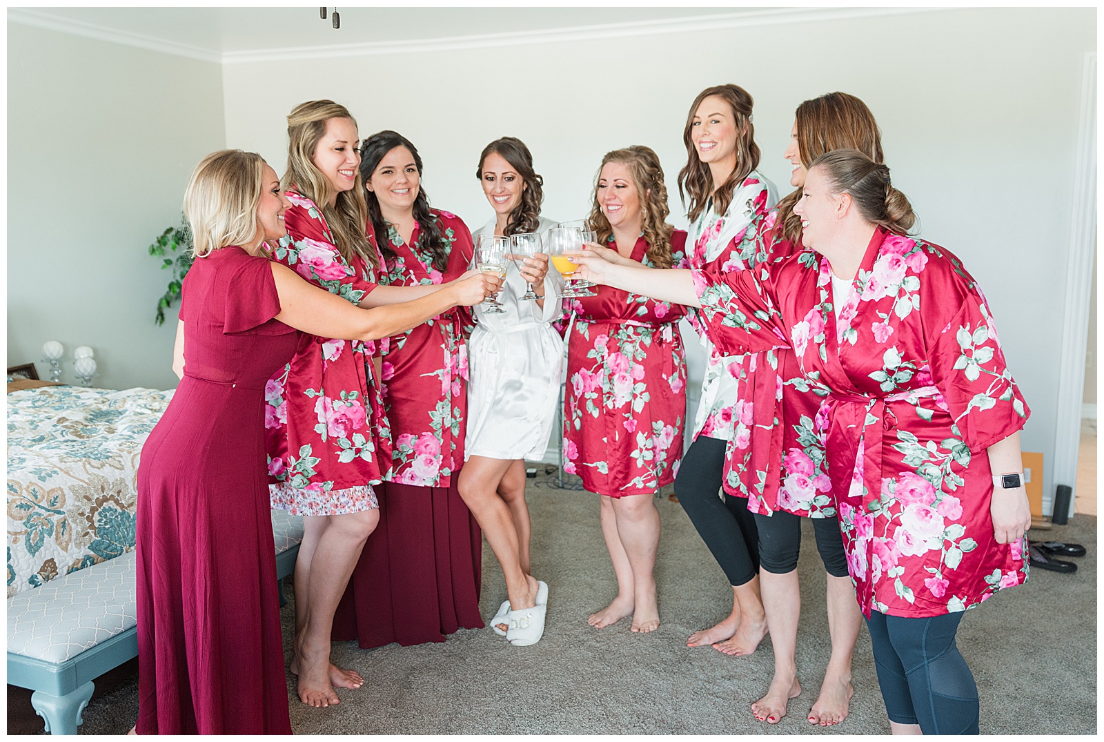 group of women holding champagne glasses smiling and wearing pink robes