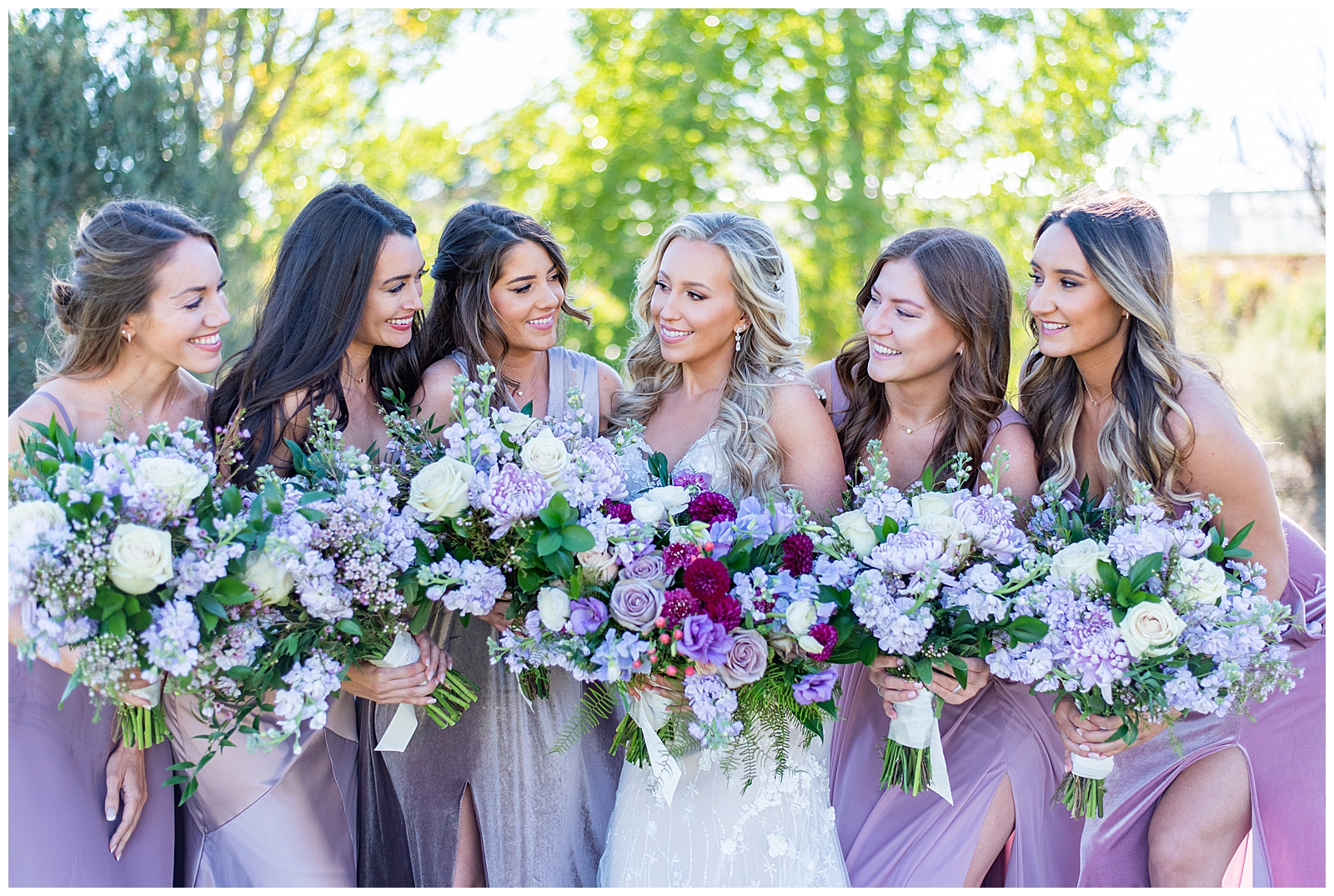 bridesmaids in purple dresses standing with the bride in the middle