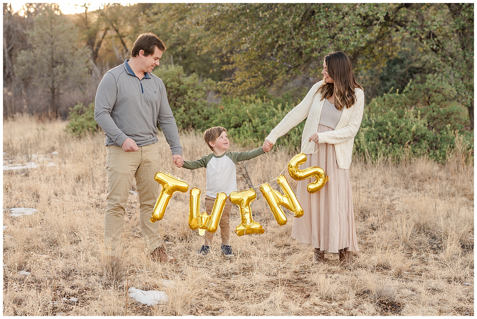 mom, dad, and son holding a sign that says "twins"