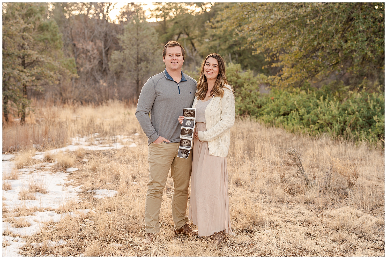 a man and woman standing together holding a sonogram