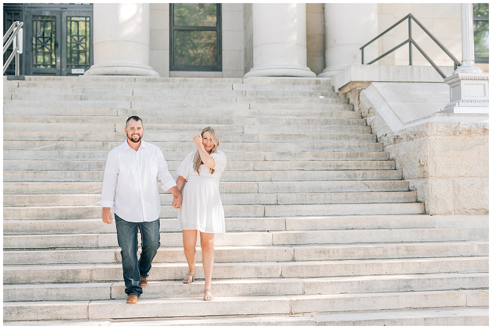 man and woman standing on steps wearing white looking at camera smiling