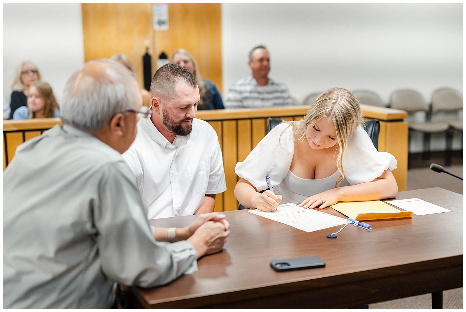 man and woman sitting down signing document on brown desk
